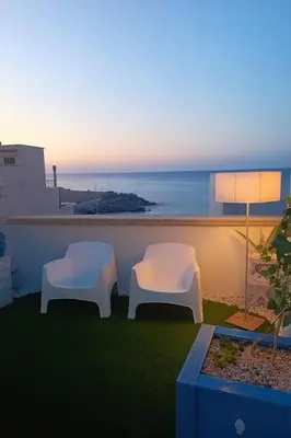 two white chairs on a balcony with a view of the ocean at Matilde Boutique Hotel by AR Group Hotels in Isola delle Femmine