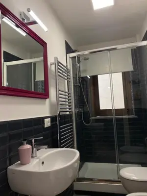 a bathroom with a sink and a shower with a mirror at 3Sisters Apartments in Palermo