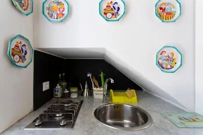 a kitchen with a sink and a stove and plates on the wall at 3Sisters Apartments in Palermo