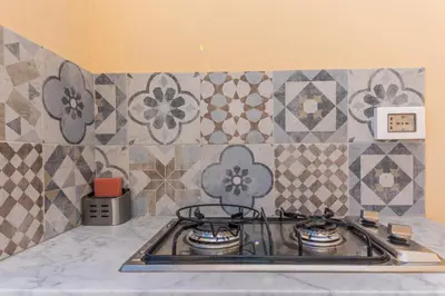 a stove top in a kitchen with tiles on the wall at Casa Colibrì - Solemar Sicilia in Santa Flavia