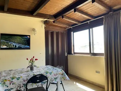 a room with a table with chairs and a television at Suite de la Sicilienne in Castellammare del Golfo