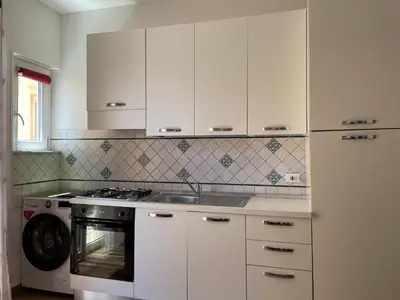 a kitchen with white cabinets and a stove top oven at Suite de la Sicilienne in Castellammare del Golfo