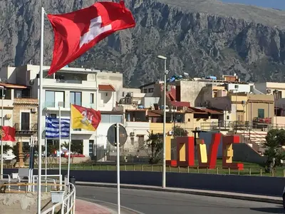 a group of flags flying in front of a city at Charm Holiday in Terrasini