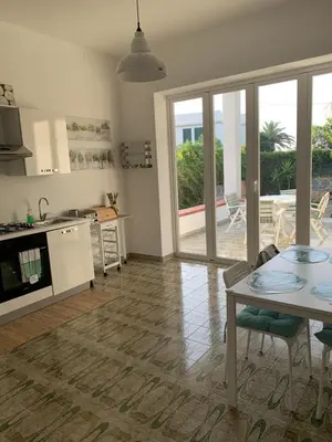 a living room with a table and a kitchen with sliding glass doors at Casa Vacanze Astori in Trabia
