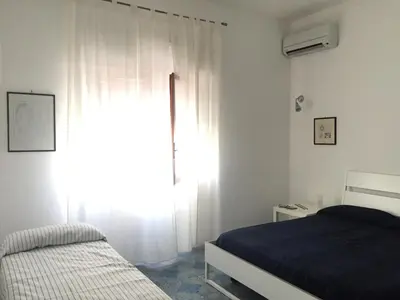 a bedroom with a bed and a window with white curtains at Casa Vacanze Astori in Trabia