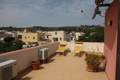 a balcony with chairs and a view of a city at Locanda Lighea Rooms in San Vito lo Capo
