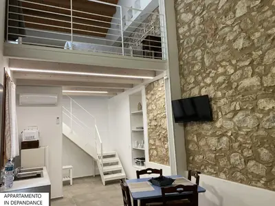 a room with a stone wall and a table and chairs at Tenute Plaia Agriturismo in Scopello