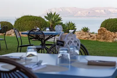 a table and chairs with a view of the ocean at Tenute Plaia Agriturismo in Scopello