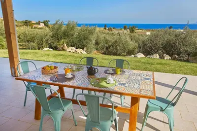 a wooden table with chairs and a table with food on it at Villa dell'Artista in Scopello