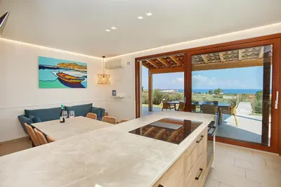 a kitchen and dining room with a view of the ocean at Villa dell'Artista in Scopello