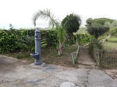 a gray fire hydrant sitting on a sidewalk next to a garden at Villa Belvedere Michelle in Trappeto