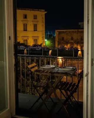 a table and chairs on a balcony at night at Petrosino in Palermo