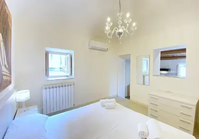 a white bedroom with a bed and a chandelier at Solemar Sicilia - Monacò rooms in Palermo