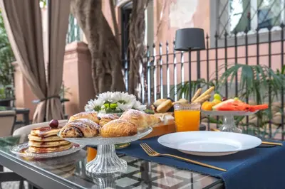 a table with bread and pastries and orange juice on it at L' Hôtellerie Easy Suites in Palermo