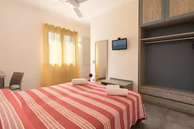 a bedroom with a bed with a red and white striped blanket at B&B Reef and Dream in San Vito lo Capo
