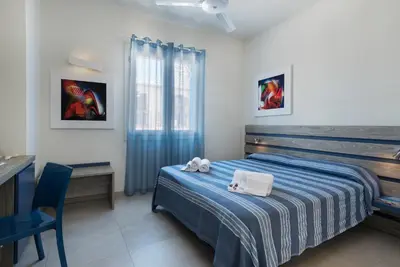 a bedroom with a bed with a blue blanket and a desk at B&B Reef and Dream in San Vito lo Capo