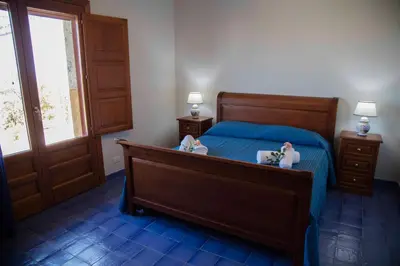 a bedroom with a bed with blue sheets and a window at Terrazze sul Tirreno in Lascari
