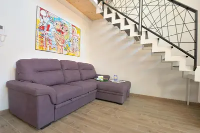 a living room with a couch and a staircase at Alla Corte Maqueda in Palermo