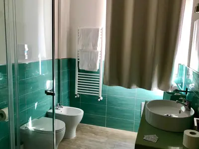 a green bathroom with a sink and a toilet at Mondello Beach Rooms - by the sea in Mondello