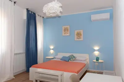 a small room with a white bed and blue walls at Mondello Beach Rooms - by the sea in Mondello