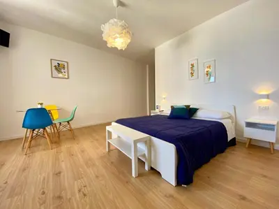 a bedroom with a bed and a table and chairs at Mondello Beach Rooms - by the sea in Mondello