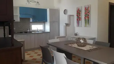 a kitchen with blue cabinets and a table and chairs at Casa Vacanze Reginotte in Balestrate