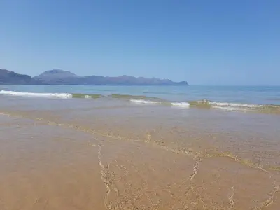 a group of people sitting on a rocky beach at Maui apartament in Alcamo