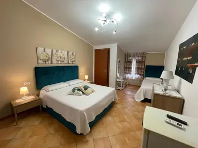 a hotel room with two beds and two tables at La Rosa Blu in San Vito lo Capo