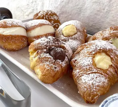 a tray of pastries and donuts on a table at La Rosa Blu in San Vito lo Capo