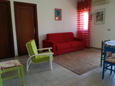 a living room with a red couch and chairs at Sunset Flat in Isola delle Femmine