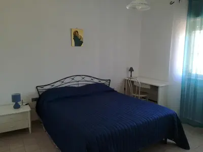 a bedroom with a bed with a blue striped blanket at Sunset Flat in Isola delle Femmine
