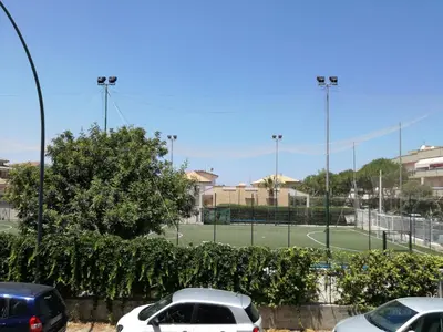 a tennis court with two cars parked in a parking lot at Sunset Flat in Isola delle Femmine