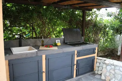 a outdoor kitchen with a grill and a sink at Azzurra Tresor in Scopello