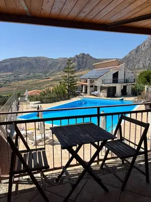 a table and chairs on a balcony with a swimming pool at Kairos B&B in San Giuseppe Jato