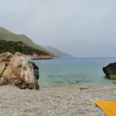 a beach with the ocean and a rock at Maison de Soleil in Scopello