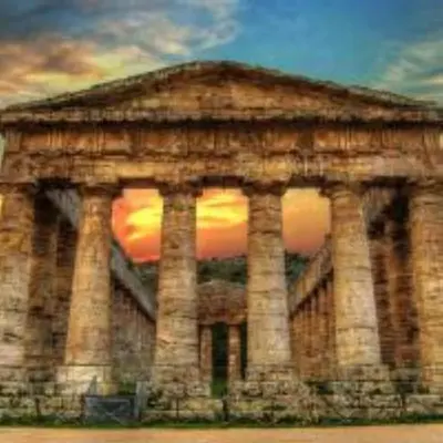 a stone building with a sunset in the background at Maison de Soleil in Scopello