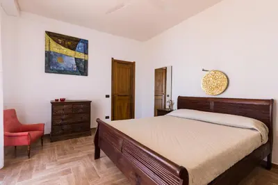 a bedroom with a bed and a red chair at Vero Sicily - Villa San Giorgio in Cinisi