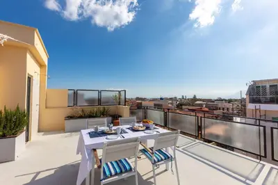 a balcony with a table and chairs on a roof at Maison Brigitte - Solemar Sicilia in Santa Flavia