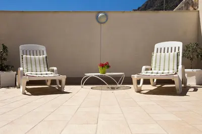 two white chairs and a table in a patio at 4Canti Case Vacanze in Castellammare del Golfo