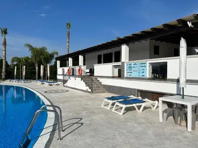 a swimming pool with chairs and a building at Residence Hydria in Campofelice di Roccella
