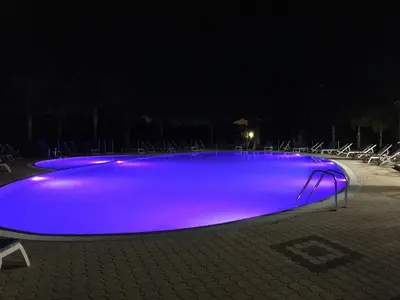 a swimming pool lit up purple at night at Residence Hydria in Campofelice di Roccella