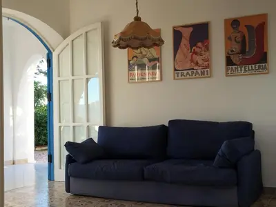 a living room with a blue couch and an open door at villa Anna Silvia Makari fiction rai 1 Casa Saverio La Manna in San Vito lo Capo