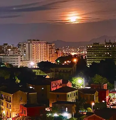 a view of a city at night with the moon at Gebel Grin in Palermo