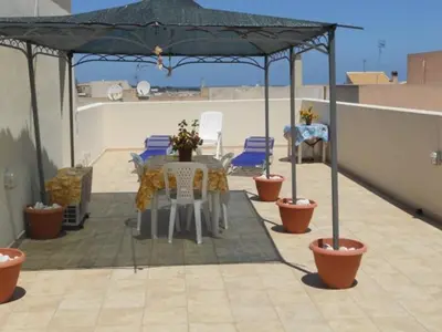 a patio with a table and chairs under an umbrella at Case vacanza Cristina site in Antico Baglio e in via Abruzzi n 161 in San Vito lo Capo
