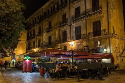 a group of people sitting at tables outside a building at Vittorio Emanuele Appartamenti in Palermo