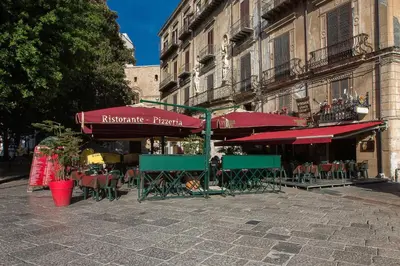 an outdoor cafe with tables and chairs and umbrellas at Vittorio Emanuele Appartamenti in Palermo