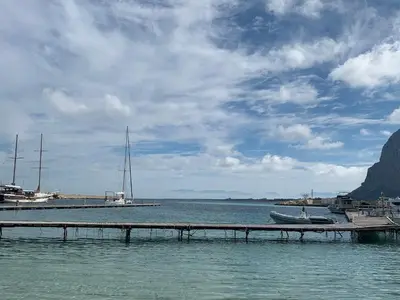 a dock in a body of water with a boat at Villa Ancora B&B in San Vito lo Capo