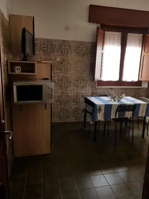 a kitchen with a table with chairs and a microwave at Bilocale Mini Very in San Vito lo Capo