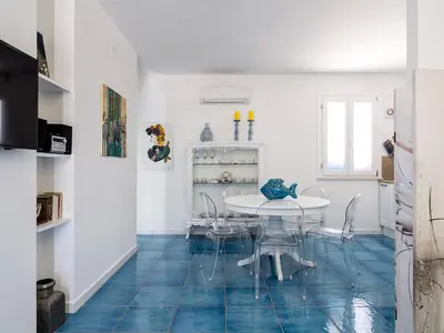 a dining room with a white table and blue floors at Spuma di Mare - Riccio in San Vito lo Capo