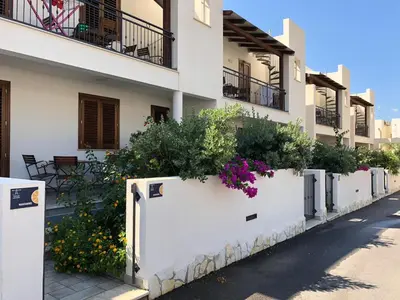a white fence with flowers in front of a building at Case Vacanza appartamenti Trinacria in San Vito lo Capo